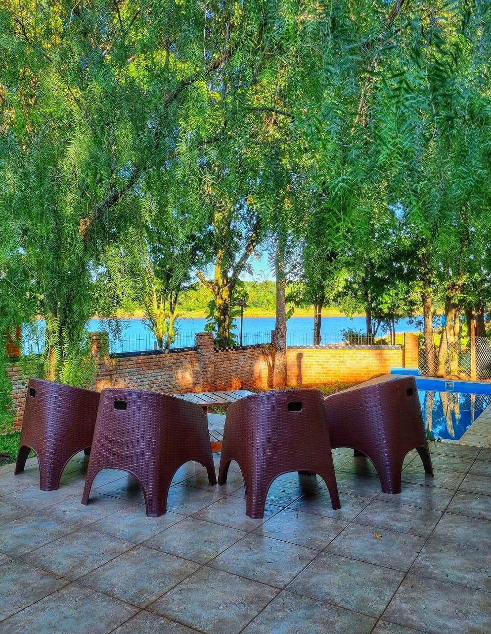 Mesa y sillas bajo los árboles, con el lago detrás