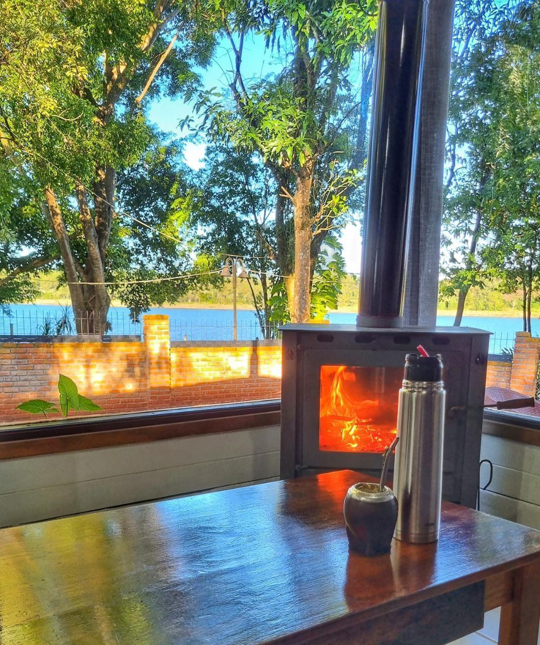 La salamandra encendida, el mate y el termo sobre la mesa